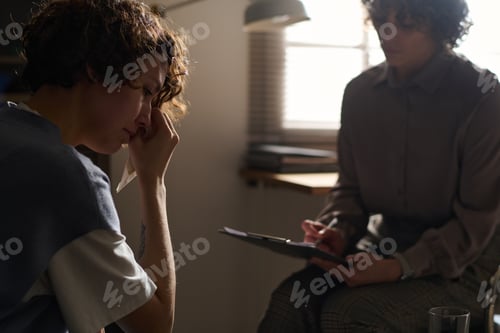 Preview: Focus on young crying brunette woman visiting her psychotherapist