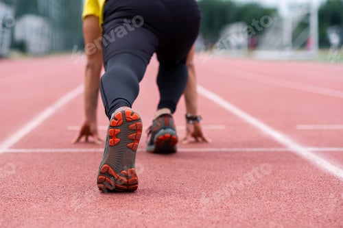 Preview: Runner standing in low start position ready to run along red rubberized track on ground