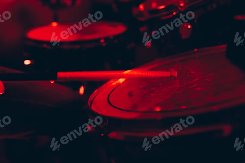 Preview: Man with drumsticks playing on drums in redness