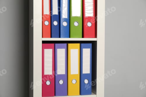 Preview: Colorful binder office folders on shelving unit near light grey wall