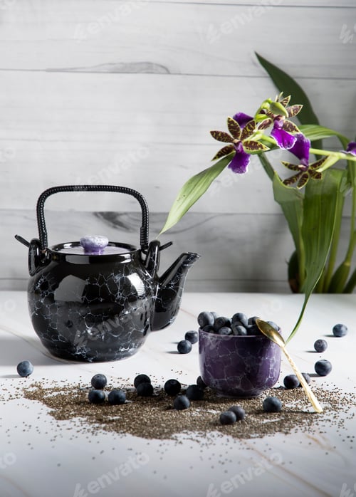 Preview: still life with a black ceramic teapot and a tea cup with blueberries on a light background