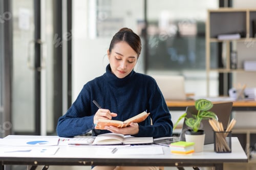 Preview: Young Asian professional business woman office worker analyst sitting at desk working on laptop