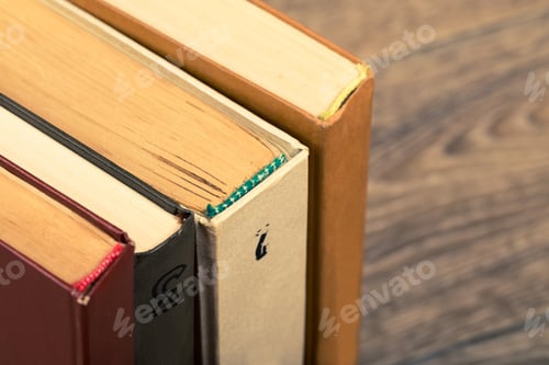 Preview: Various vintage books stacked on a wooden surface in a well-lit room