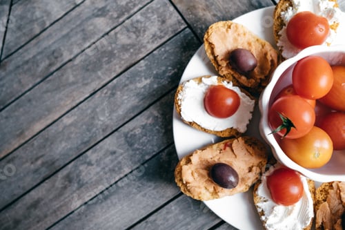 Preview: Bruschetta with soft cream cheese, olives, cherry tomatoes and pate on the plate. Space for text
