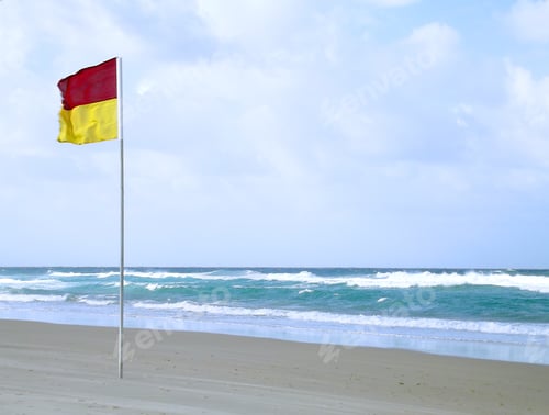 Preview: Safety warning flag on a windy day at the beach - swim between the flags