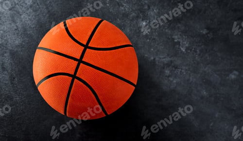 Preview: High angle shot of a single basket ball placed on top of a dark background inside of a studio