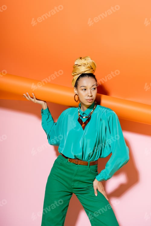 Preview: Trendy african american model in summer outfit posing with orange and pink background