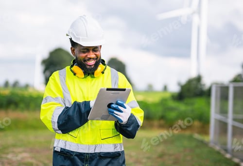 Preview: man in yellow and black safety suit is smiling while looking at tablet