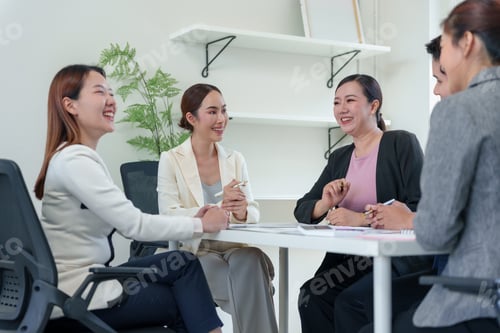 Preview: Asian businesswomen discussing and laughing during a meeting