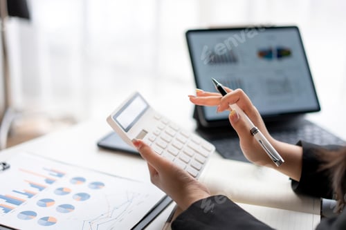 Preview: A woman is sitting at a desk with a calculator and a pen