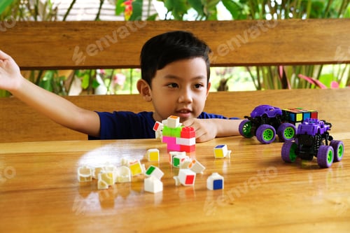 Preview: young boy in a blue shirt builds with colorful blocks at a wooden table