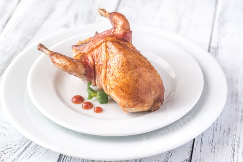 Preview: Baked quail wrapped in bacon on the plate