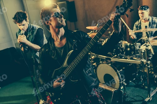 Preview: selective focus of good-looking guitarist in sunglasses playing electric guitar near rock band