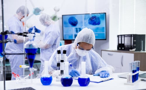 Preview: Female scientist with microscope near and smoking blue solution