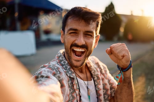 Preview: Happy man having fun during open air music festival while taking selfie and looking at camera.