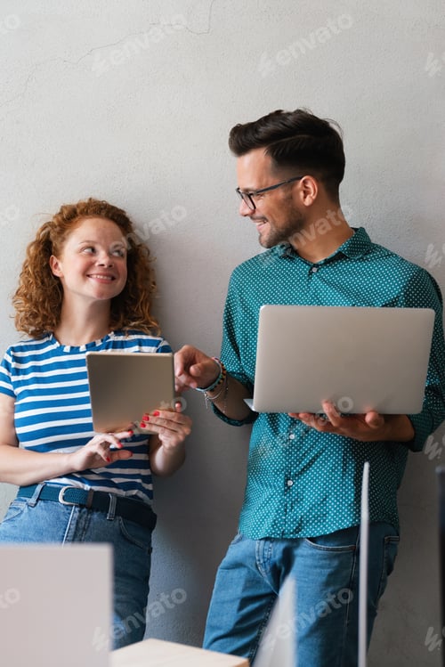 Preview: Young manager talking with experienced colleague while using computer in office.