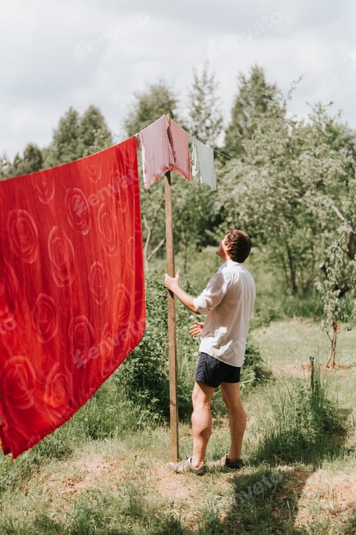 Preview: candid young mature choring man chore homework and hanging the laundry to dry on a clothesline on th