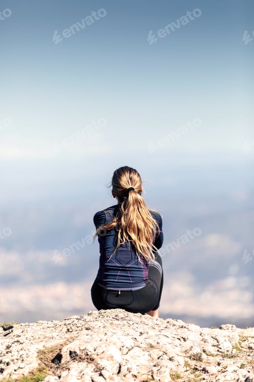 Preview: Trail runner sitting and taking a break while looking landscape