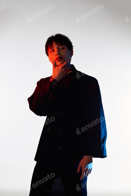 Preview: Stylish asian man poses confidently with modern flair against a contrasting light backdrop