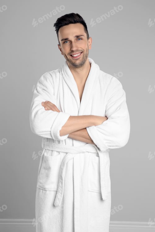 Preview: Happy young man in bathrobe on light grey background
