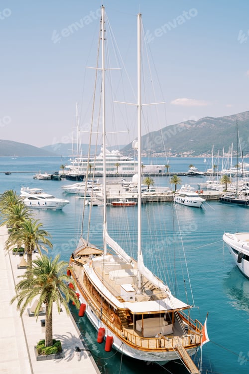 Preview: Luxury sailing yacht stands on a pier with green palm trees with a bridge lowered ashore