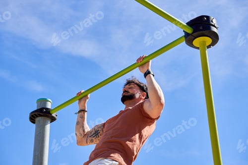 Preview: A young athlete performs pull-ups at an outdoor calisthenics park,