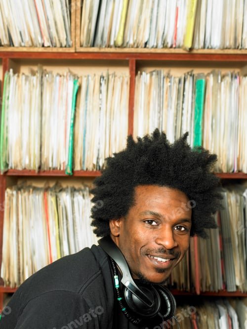 Preview: DJ smiling in front of a collection of vinyl records