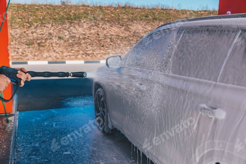 Preview: Сar wash self-service. Man washing luxury vehicle with white foamy detergent.