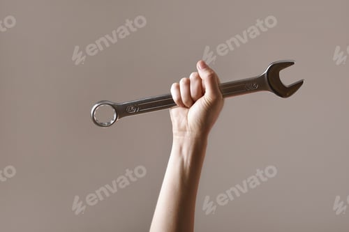 Preview: big spanner in the woman's hand. hand holds a wrench on a gray background. Combination wrench.