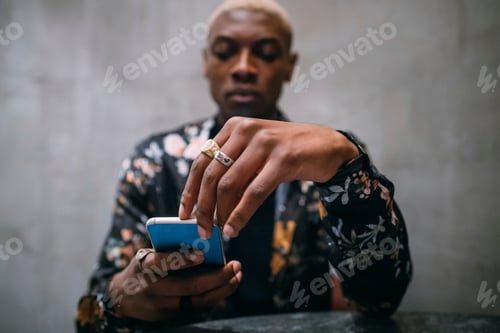 Preview: Stylish man using cellphone, concrete wall background