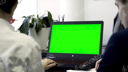 Preview: Young women working in office, sitting in chairs in front of computer with green screen, rear view