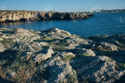 Preview: woman traveler sitting on stones near the sea landscape beach sunset clear water
