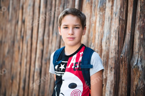 Preview: Portrait of a toddler boy with backpack against wooden wall