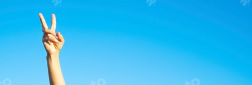 Preview: Stop war love peace with v victory gesture hands and fingers against blue sky background