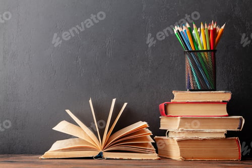 Preview: Old books on wooden table and blackboard