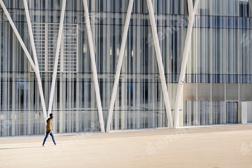 Preview: black man walking in front of a modern building