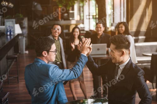 Preview: large business team showing unity with their hands together, business team celebrating
