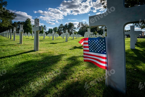 Preview: American flag standing at the gravestone of a killed soldier at the war cemetery in Normandy