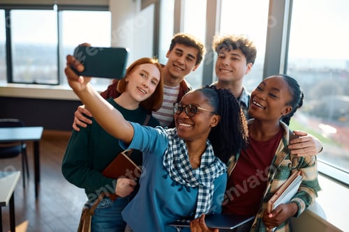 Preview: Group of happy college friends taking selfie with cell phone in the classroom.
