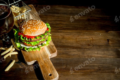Preview: Burger on a cutting Board with beer and fries.