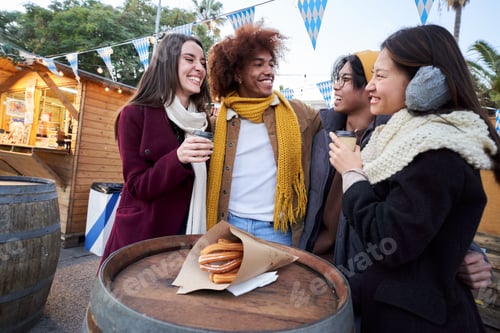 Preview: Happy smiling friends eating chocolate with churros together on street outdoors. Festival in winter.