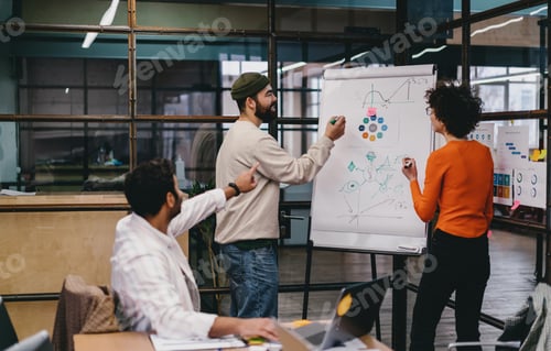 Preview: Focused diverse colleagues discussing project on board in office