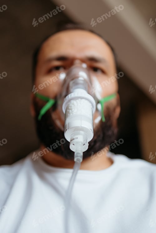 Preview: Man receiving respiratory treatment with a nebulizer mask for breathing difficulty
