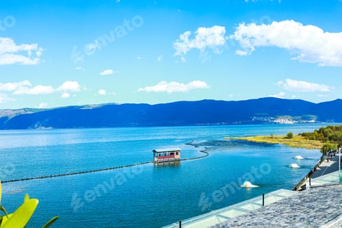 Preview: Scenic view of a blue tranquil lake surrounded by mountains on a sunny day