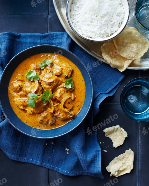 Preview: Bowl of creamy mushroom curry with rice and papadums on a dark background