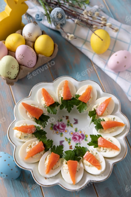 Preview: Stuffed eggs with cheese and salted salmon in the form of a carrot on a wooden table.