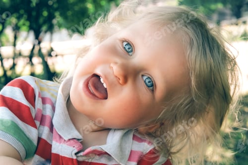 Preview: Portrait of a little blonde boy with blue eyes having fun playing outdoors in summertime.