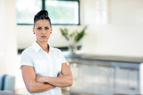 Preview: Woman standing with crossed arms in kitchen wearing white shirt beside flower vase, copy space