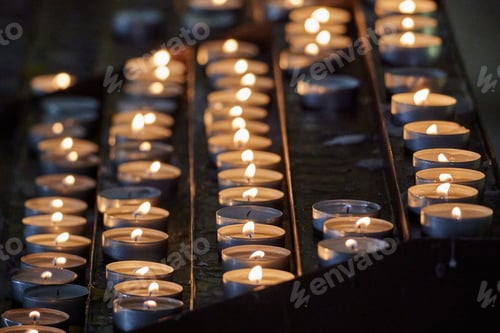 Preview: Close-up shot of multiple lit votive candles in a church setting, with a blurred out background