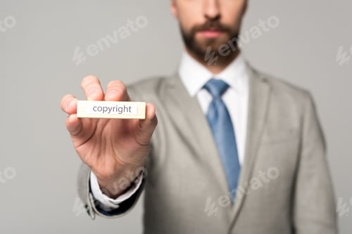 Preview: partial view of businessman showing wooden block with word copyright isolated on grey